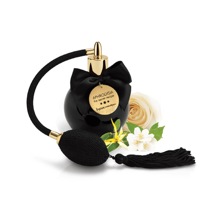 Parfum aphrodisiaque floral Aphrodisia de bijoux indiscrets, délicatement posé parmi des fleurs fraîches, offert par Oh My God'Z, incarne l'élégance et la passion avec son design noir et doré et son parfum captivant.