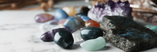 Gros plan sur une collection de pierres précieuses polies, incluant des améthystes, des quartz et d'autres minéraux colorés, disposés sur une surface en marbre, symbolisant les bienfaits spirituels et énergétiques.