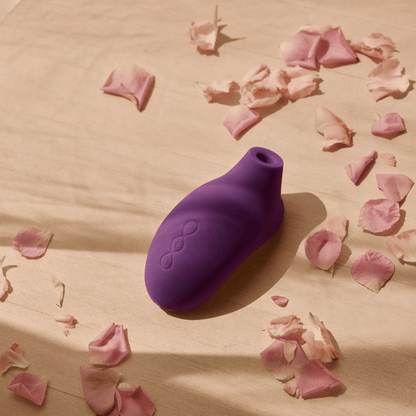 Sona 2 de Lelo capturé dans une ambiance sensuelle avec des pétales de rose, évoquant douceur et puissance, disponible sur OhMyGodz.fr.