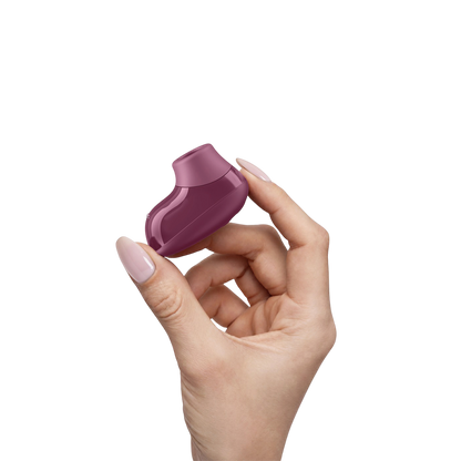 Stimulateur clitoridien Snap Womanizer prune tenu entre deux doigts, format mini en silicone brillant - Oh My God'Z