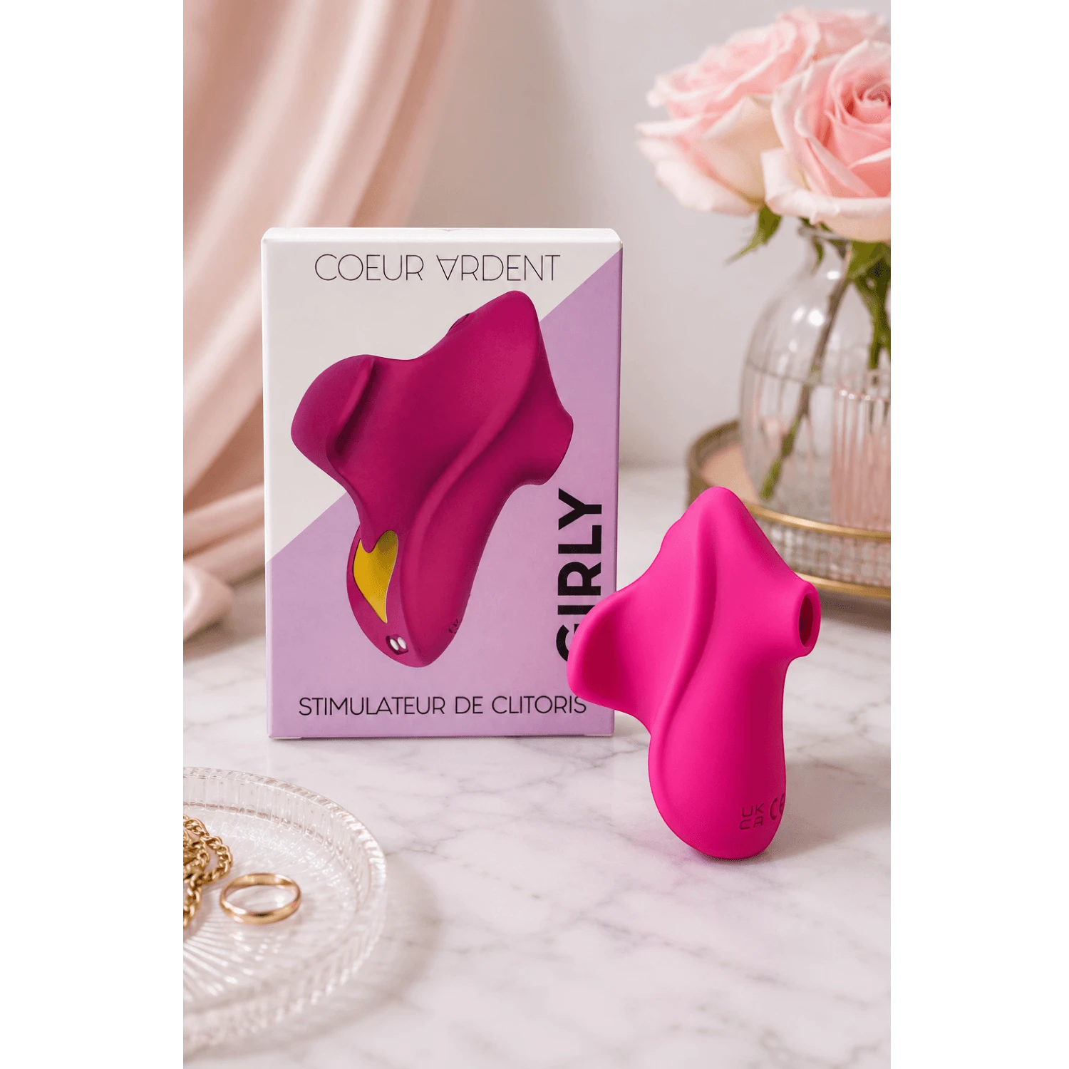 Stimulateur Girly rose fuchsia présenté avec sa boîte sur table décorative avec roses et accessoires - Oh My God'Z